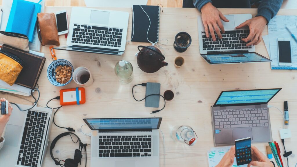 people sitting down near table with assorted laptop computers