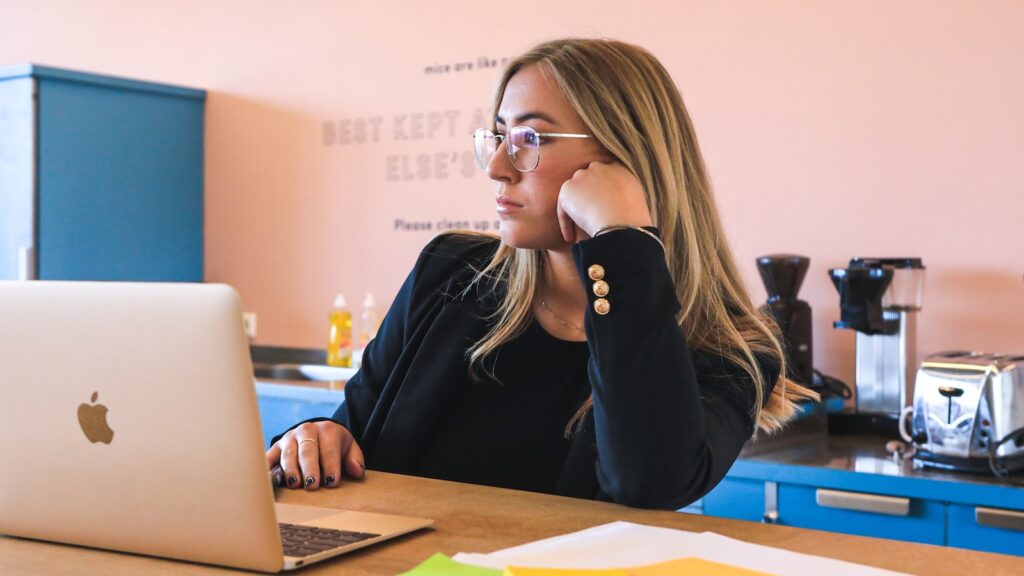 woman in black long sleeve shirt wearing black framed eyeglasses using macbook